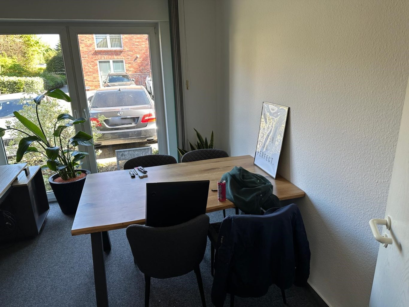 Nachher Bild Unternehmens Umzug Ein einfacher Arbeitsbereich mit Tisch, Stühlen und Pflanzen, neben einem Fenster.
