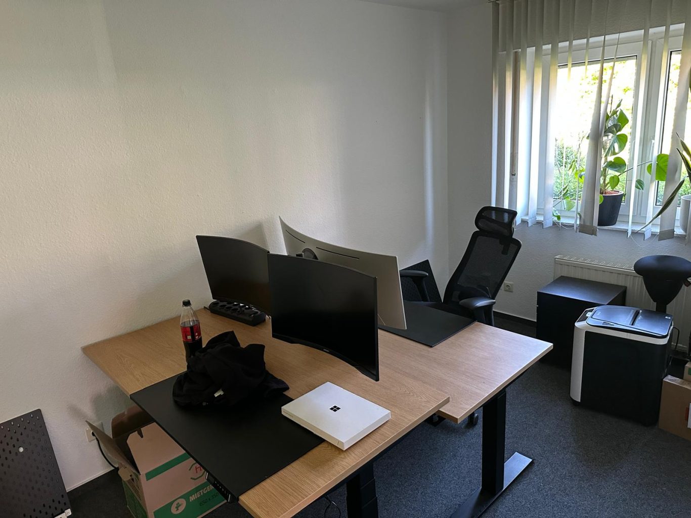 Nachher Bild Büroumzug Minimalist Büro mit zwei Monitore, Schreibtisch, Stuhl und Pflanzen am Fenster.